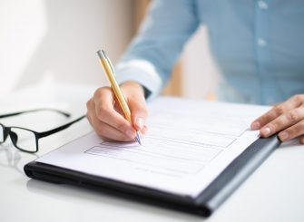 Closeup of business woman making notes in document. Entrepreneur sitting at desk and writing. Paperwork concept. Cropped view.